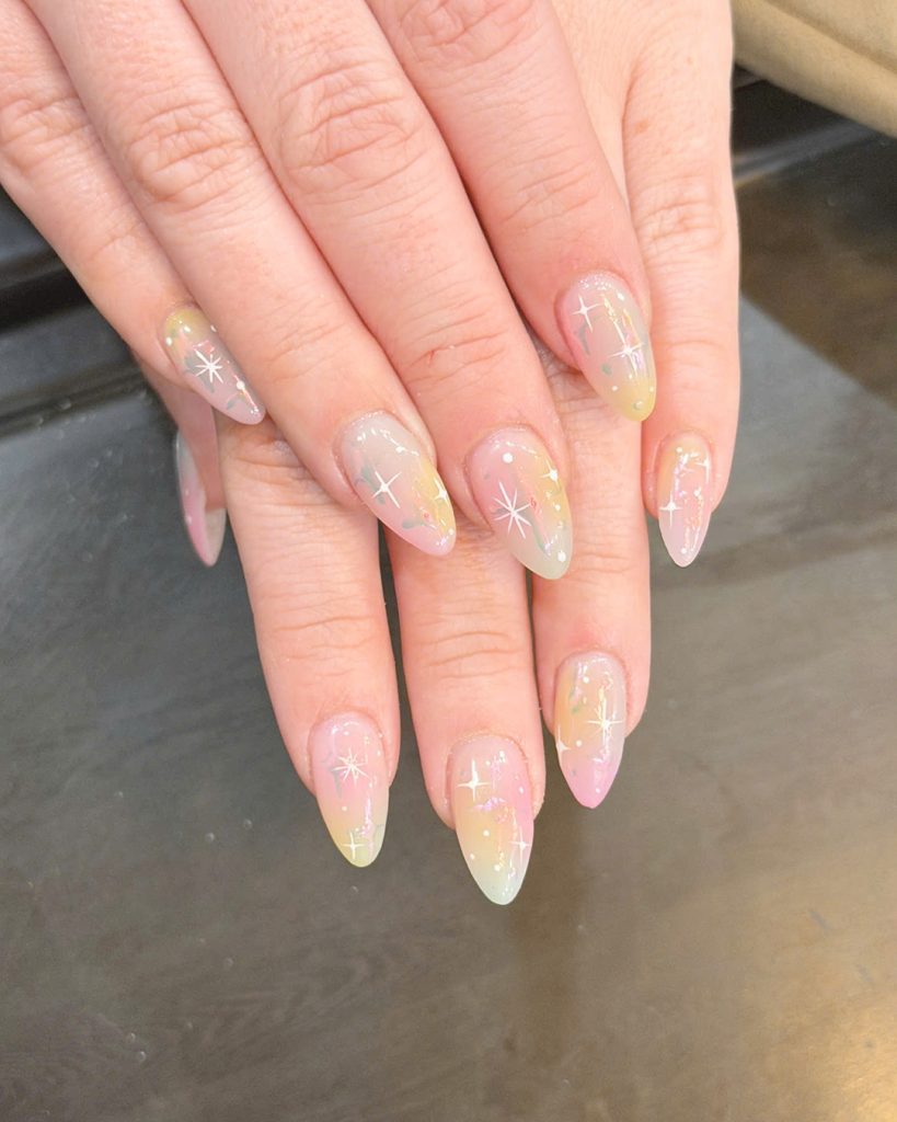 Builder Gel Nails vs. Acrylic: What Changes When You Switch 3 Sheer almond nails with a pastel yellow and pink aura, iridescent flecks and white star art