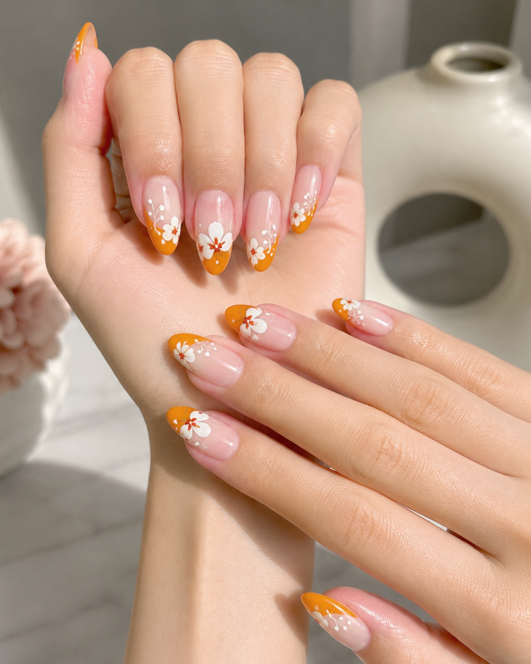 Orange French beach nails with tropical flowers and glossy almond-shaped summer manicure.