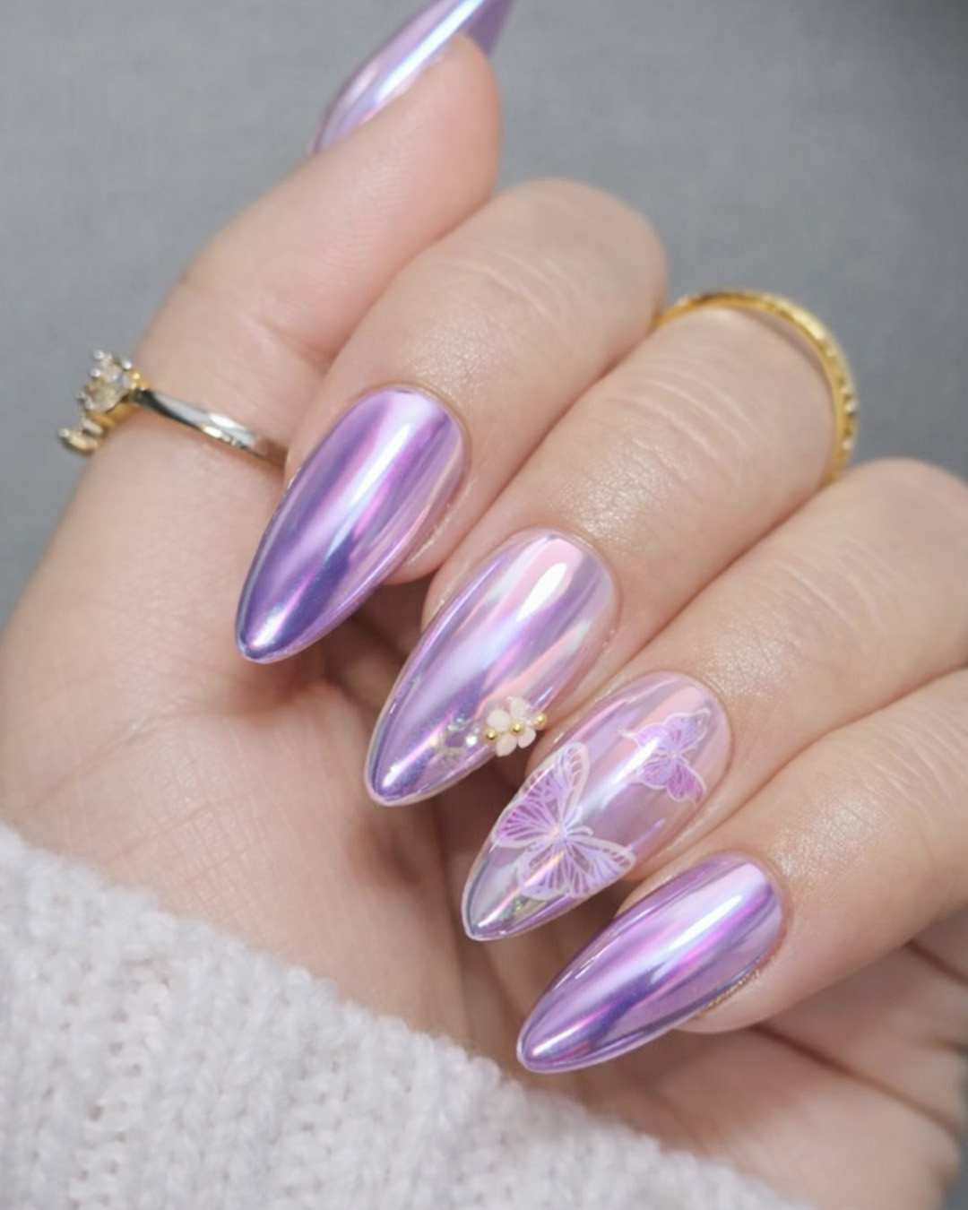 Iridescent lavender chrome nails with a color-shifting effect, decorated with butterfly and floral nail art.