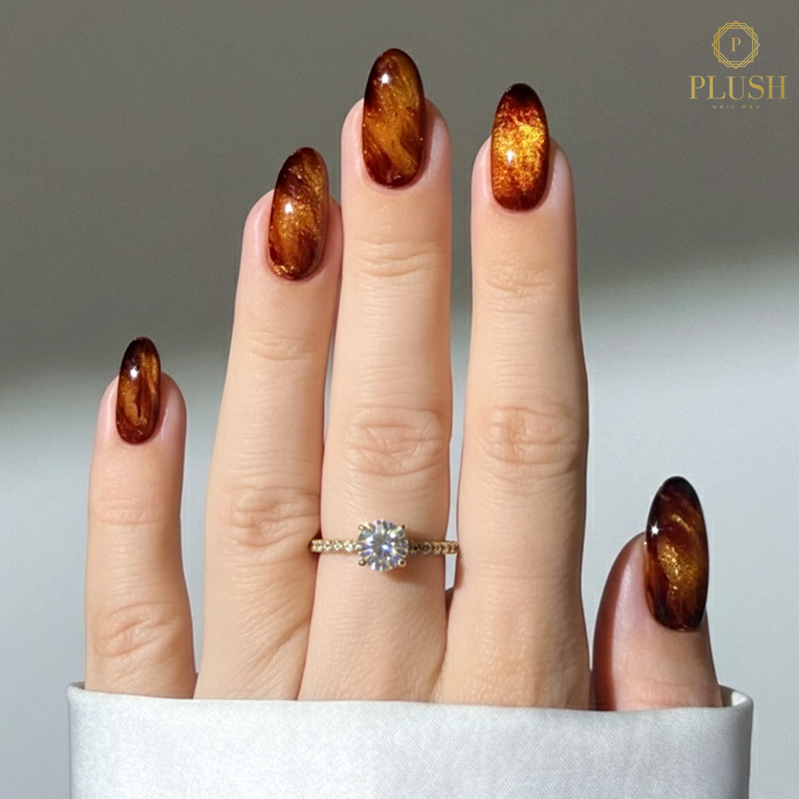 Almond nail trends for fall featuring a molten copper cat eye design with a magnetic shimmer effec