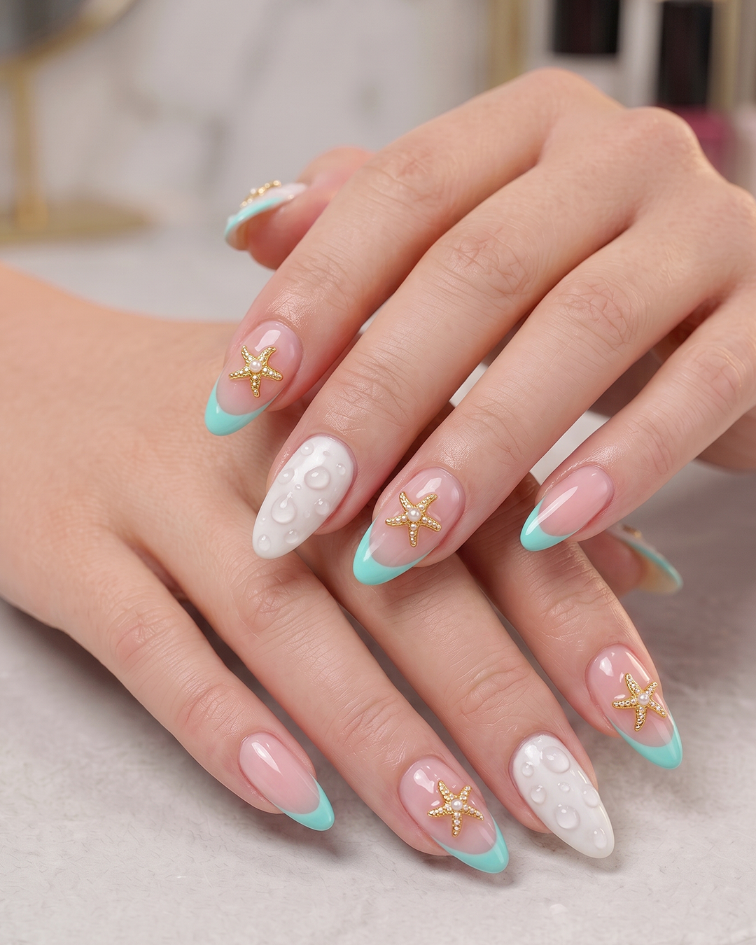 Aqua French beach nails with pearl starfish accents and water droplet nail art.