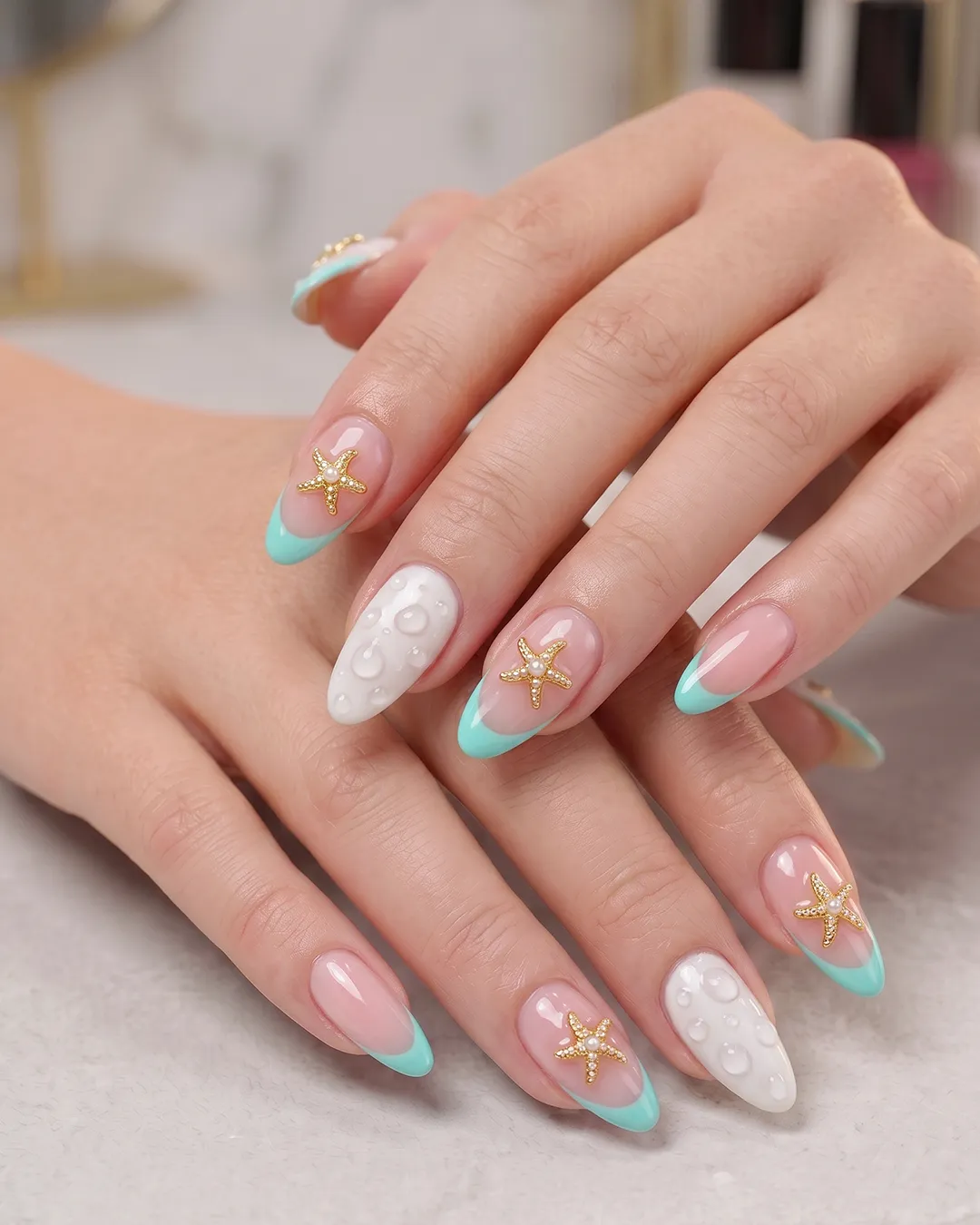 Aqua French beach nails with pearl starfish accents and water droplet nail art.