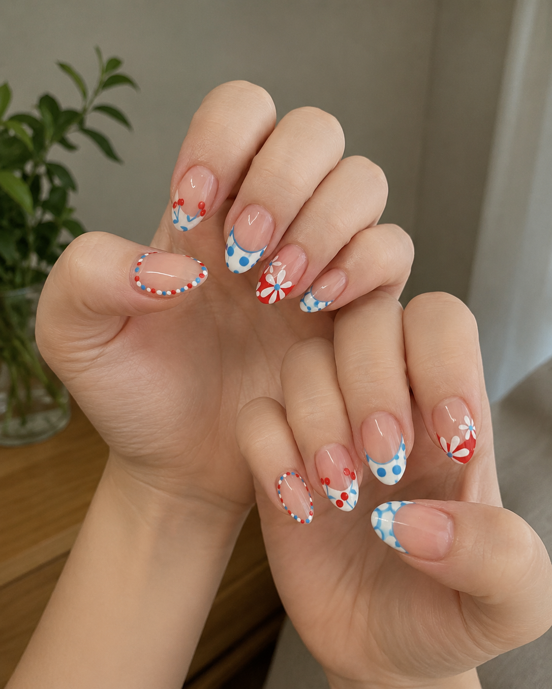 Classy Fourth of July French tip nails with blue polka dots, floral accents, and cherry details on a nude base.