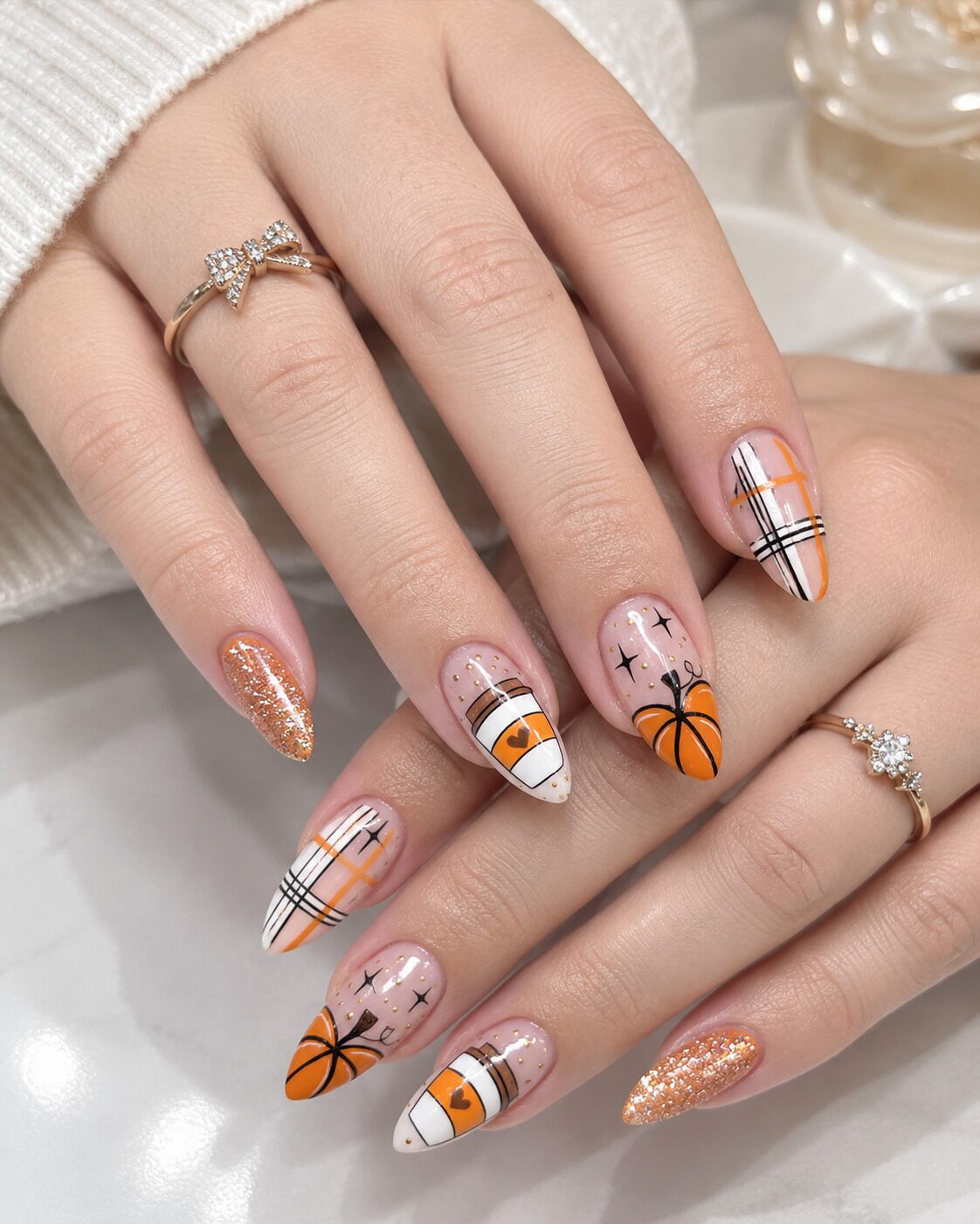 Cozy fall nail art featuring miniature pumpkin spice coffee cups and orange plaid patterns