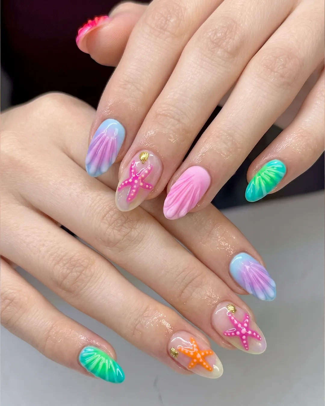 Colorful tropical beach nails featuring starfish nail art, seashell textures, ocean blue gradients, and summer vacation manicure.