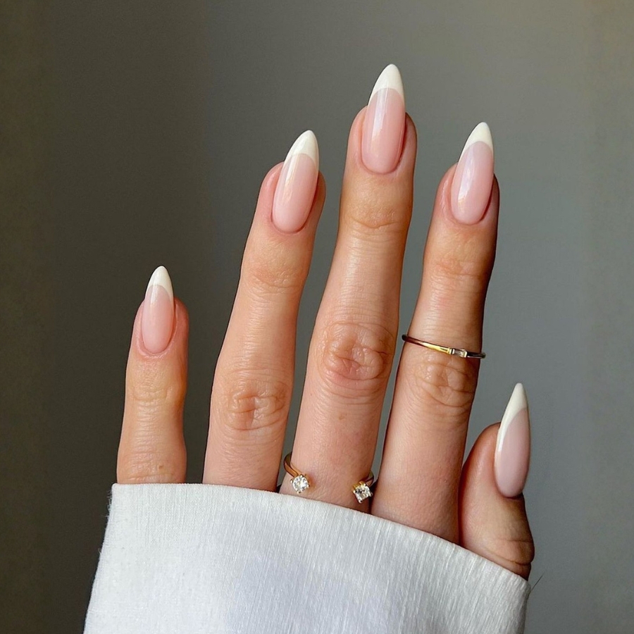 Timeless French manicure idea with crisp white tips on glossy nude almond-shaped nails.