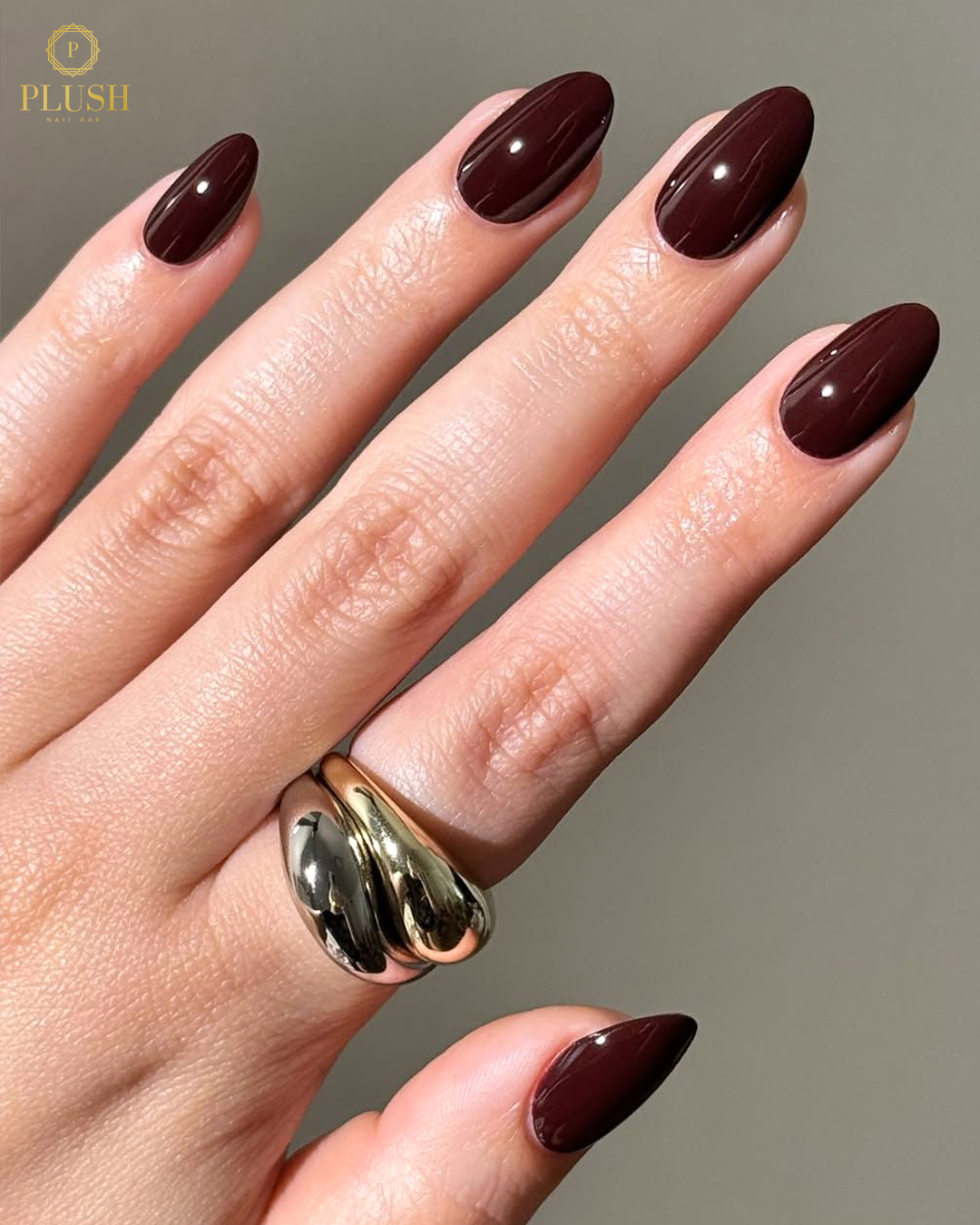 Glossy burgundy almond nails with a smooth, elegant finish at Plush Nail Bar.