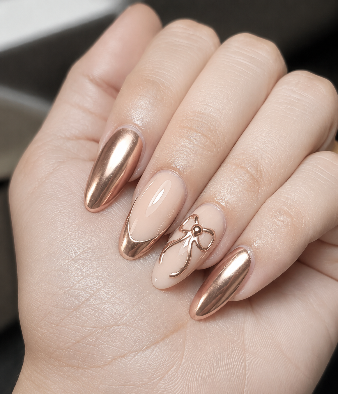 Champagne Chrome Nails combining rose chrome French tips with minimalist ribbon nail art on nude almond nails for an elegant luxury look.