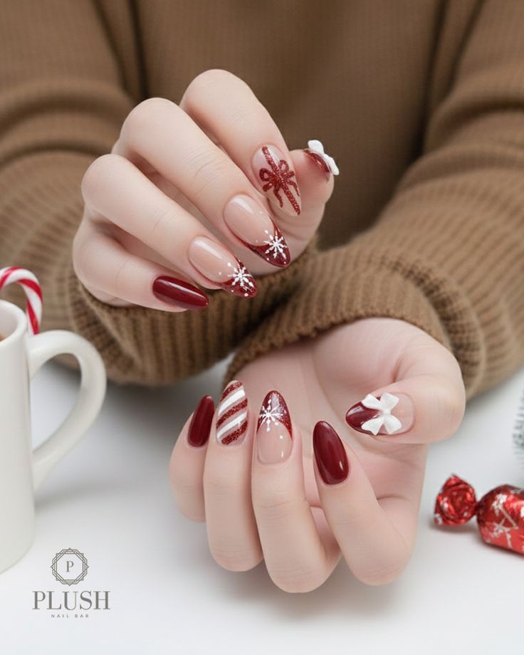 Deep wine red Christmas nails with snowflake detailing, candy-cane stripes, and glittery gift-bow accents by Plush Nail Bar