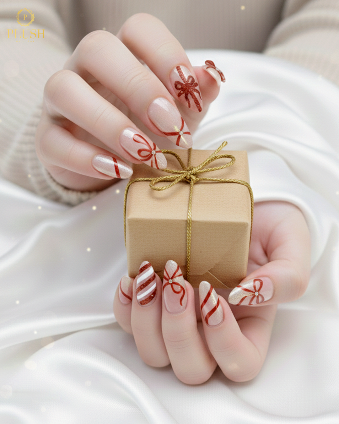 Shimmering nude base Christmas nails with red ribbon gift-wrap designs and candy-cane stripes by Plush Nail Bar