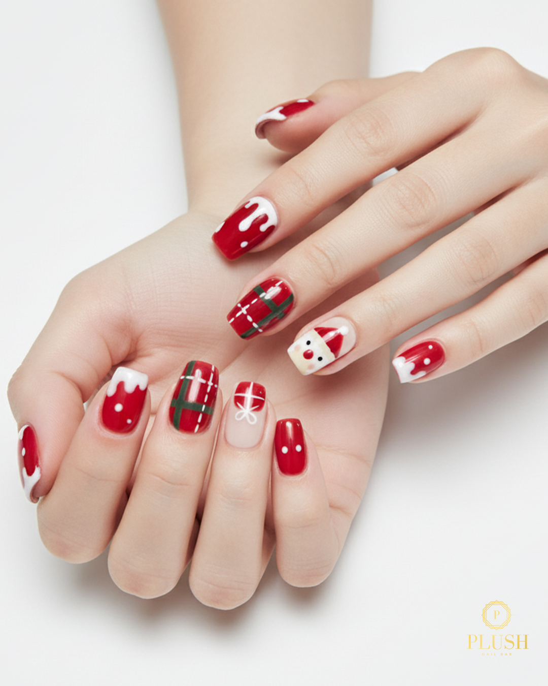 Cute red Christmas nails featuring Santa art, plaid patterns, white snow-drip tips, and festive gift ribbon designs by Plush Nail Bar.