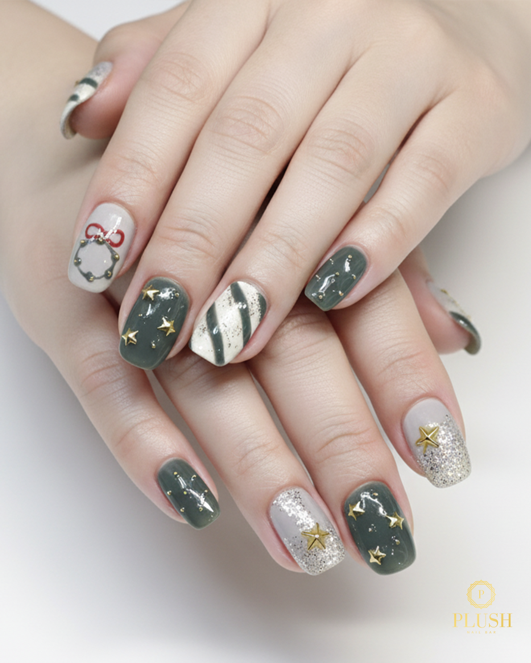 Elegant green and silver Christmas nails decorated with gold stars, glitter accents, and holiday wreath artwork by Plush Nail Bar.