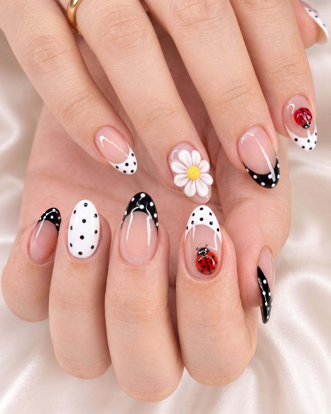 Black and white polka dot nails with ladybugs and a 3D daisy