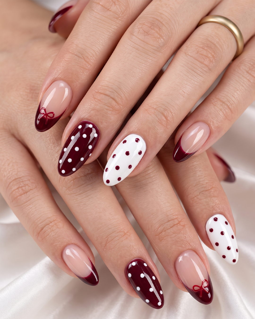 Burgundy and white polka dot nails with French tips and bow accents