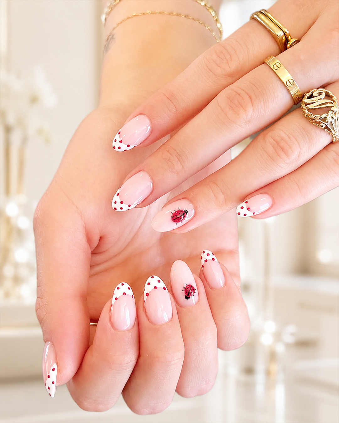 White French tip nails with red polka dots and ladybug accents