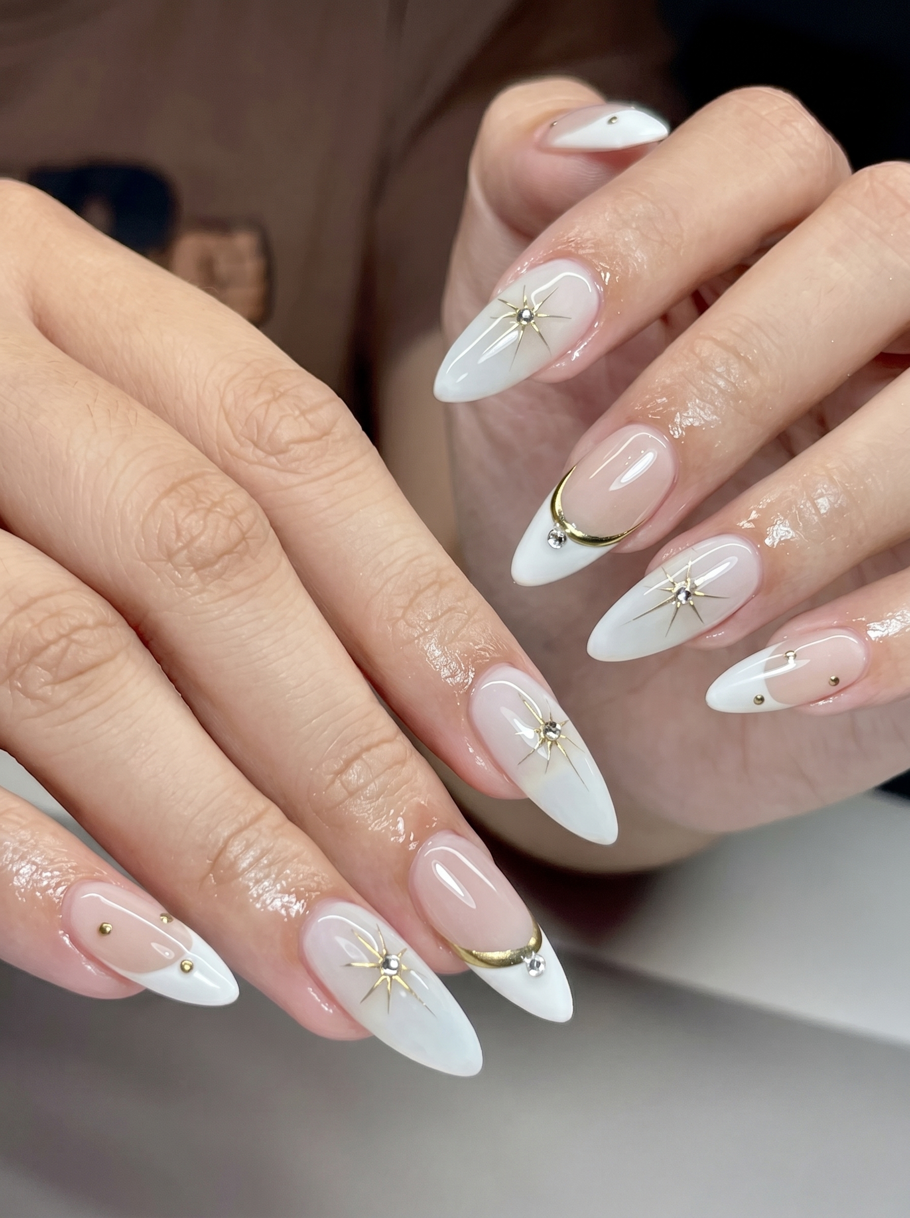 White Chrome Nails: The Stunning Trend Everyone Is Wearing in 2026 4 White chrome French tip nails with gold celestial accents and crystal details on almond nails.