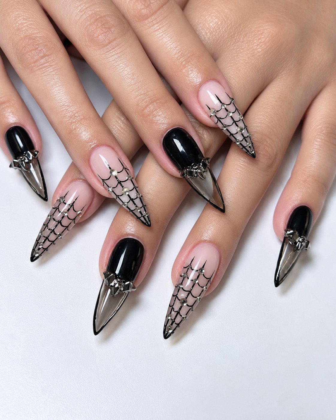 Black and nude stiletto nails with smoky tips, chrome bat charms and a crystal spiderweb lattice