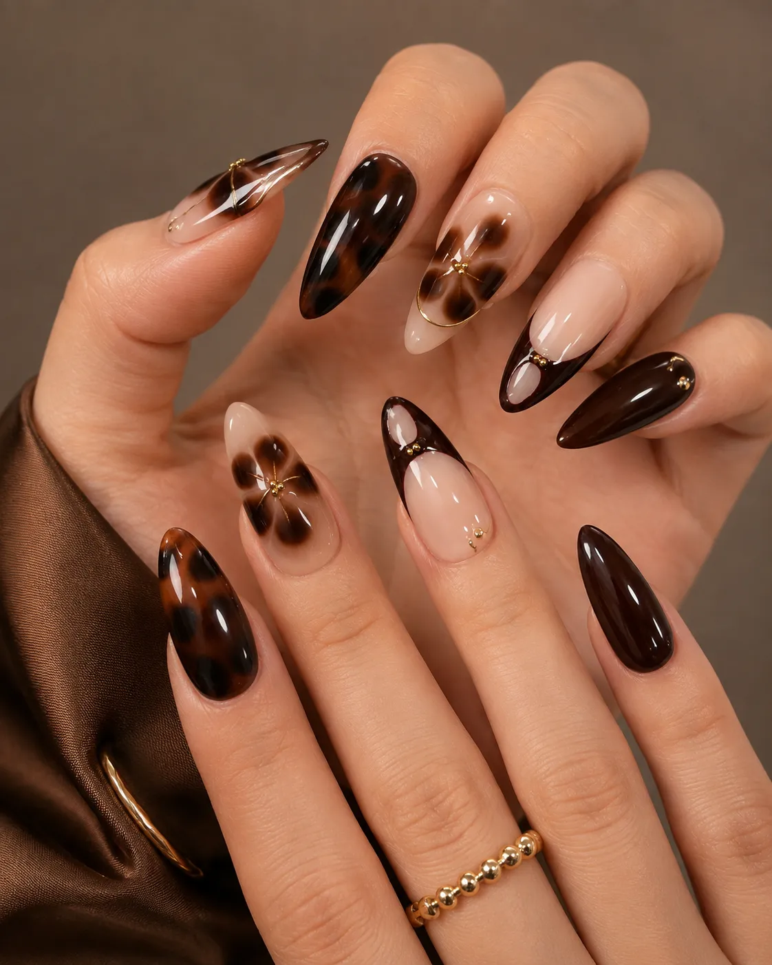 8 Ways to Wear Brown Nails This Season in Houston 2 Tortoiseshell and brown floral almond-shaped nails with gold ring accents
