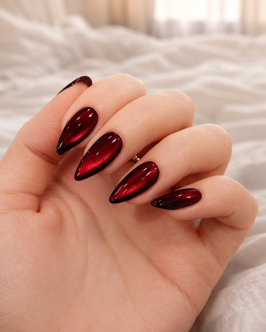 Long stiletto black cherry nails with a glossy glass finish and a red shimmer band