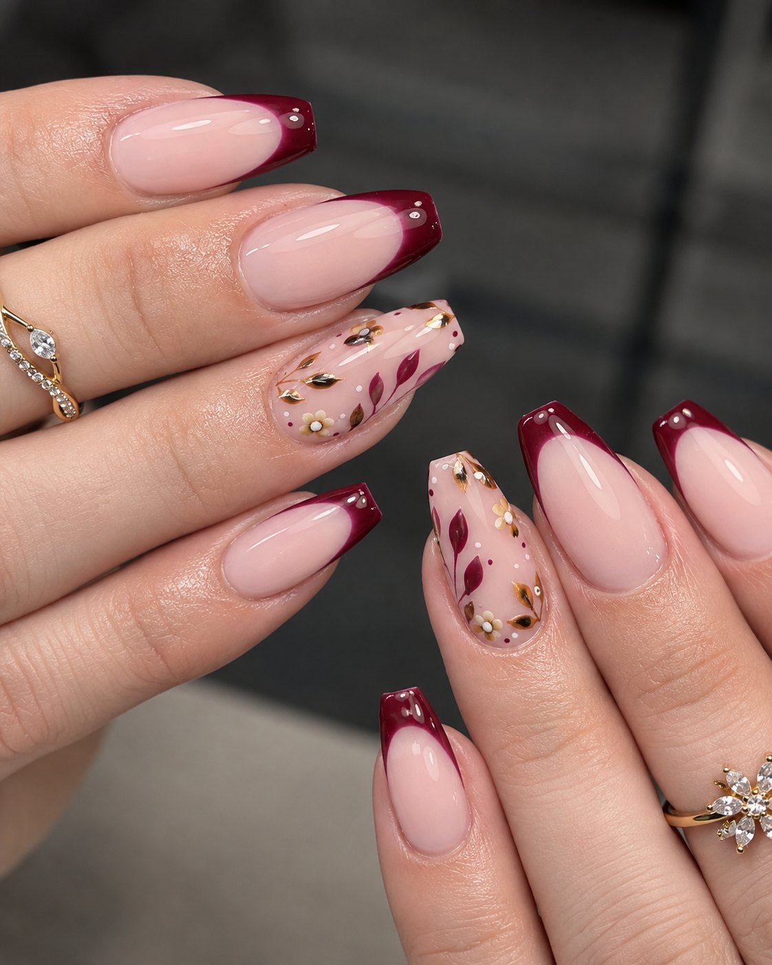 Wide burgundy French tips with crystals and a gold floral accent nail
