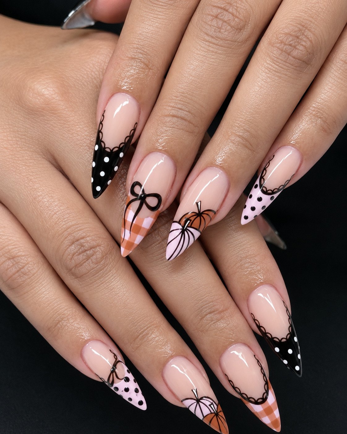 Coquette Halloween stiletto nails with lace-edged polka dot and gingham tips, black bows and pumpkins