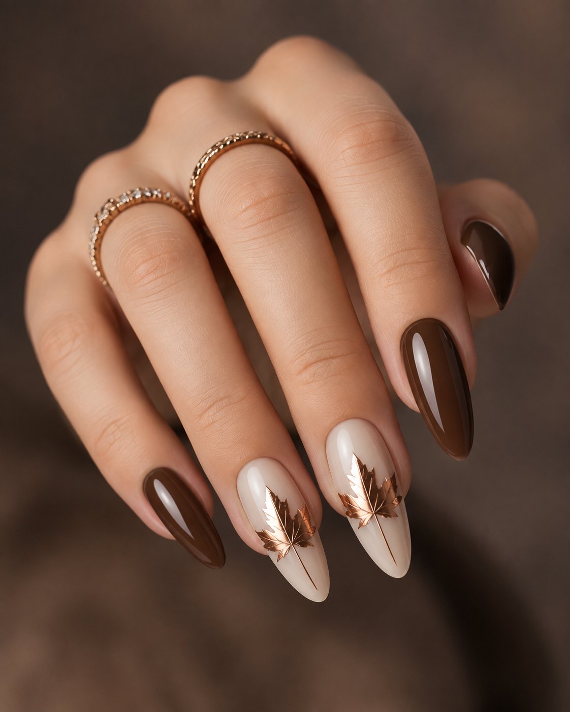 Thanksgiving Nails 2026: Simple, Warm Sets for the Holiday 3 Chocolate brown almond nails with two milky ivory accent nails each holding a copper foil maple leaf
