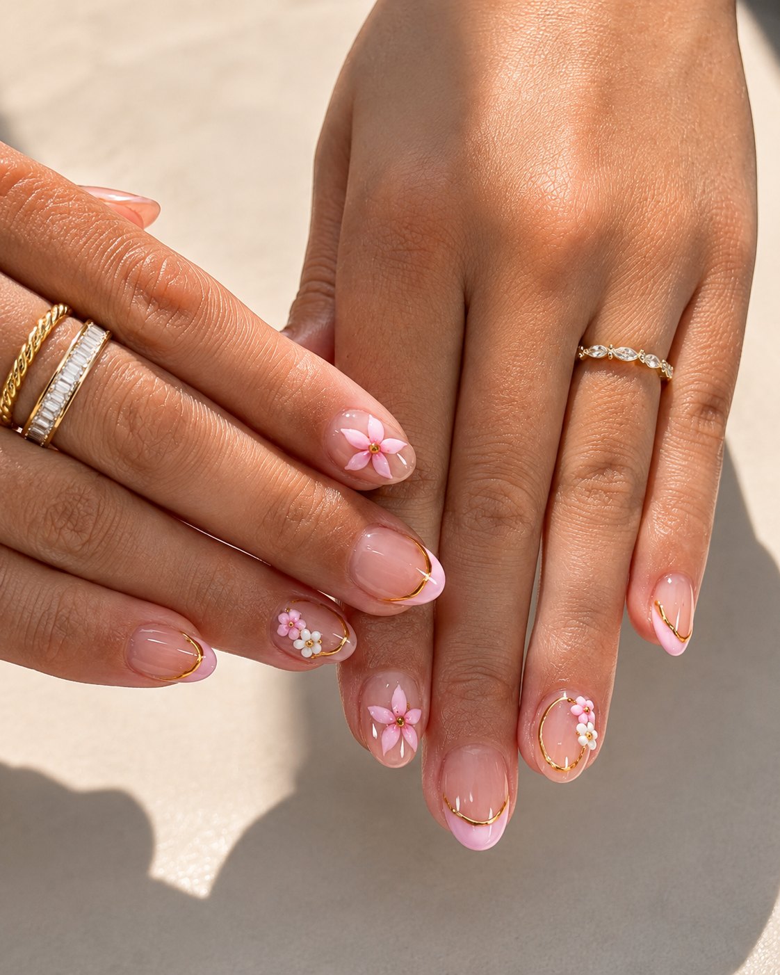Short almond homecoming nails in sheer blush with a thin gold French line and 3D pink flowers