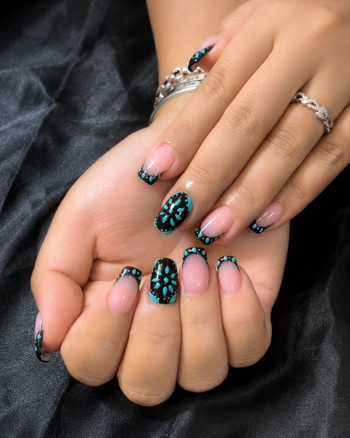 Medium squoval nails with black French tips, turquoise beading and turquoise flower accent nails
