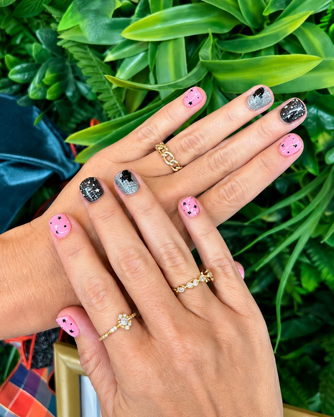Short round nails in bubblegum pink with black stars plus black and silver glitter accents