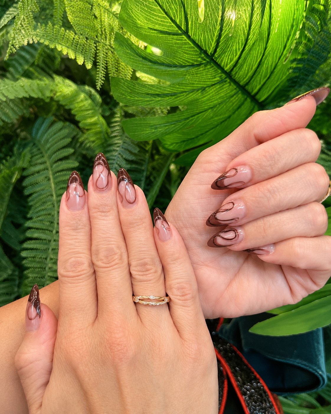 Long almond nails in sheer nude with dark chocolate brown negative-space swirls