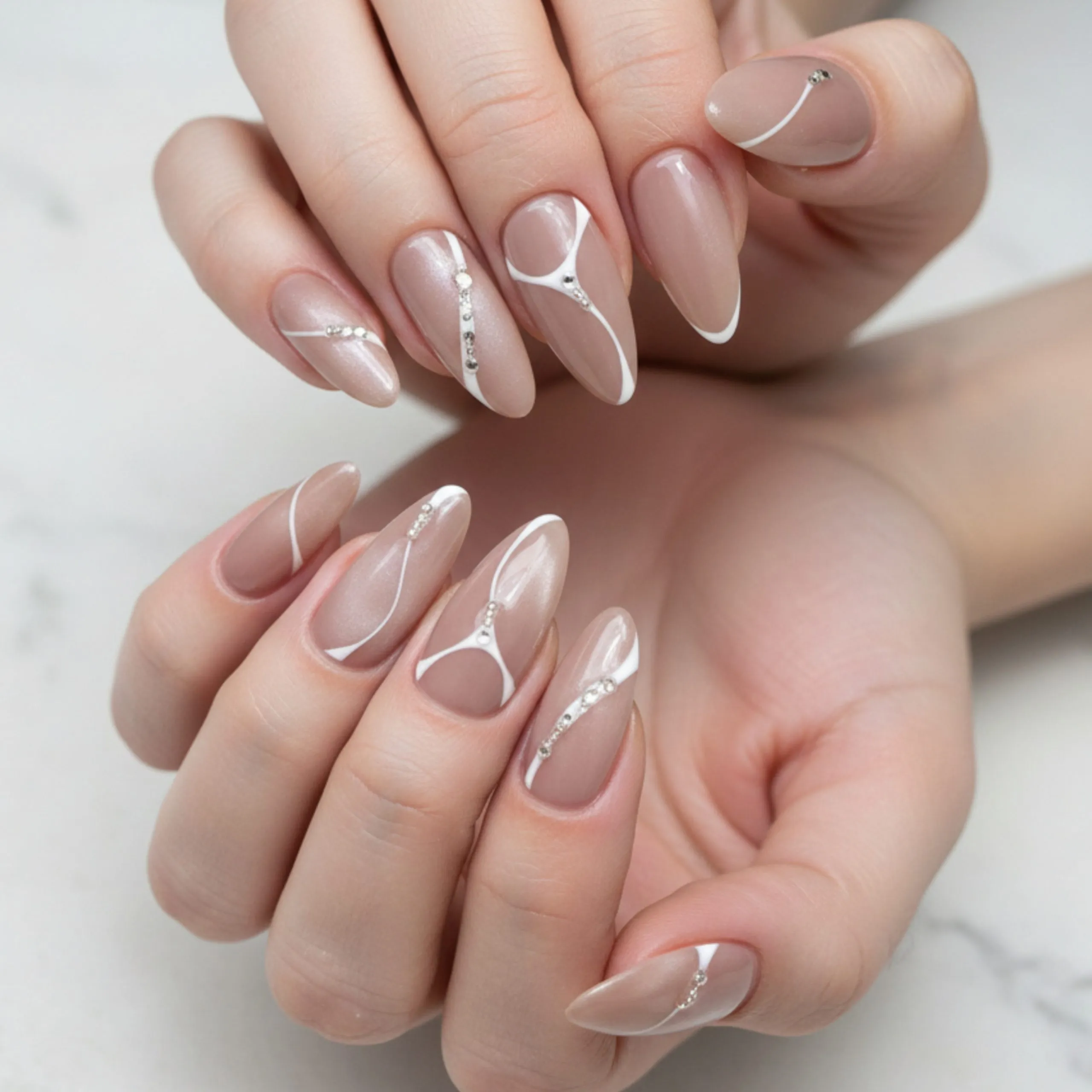 7 Homecoming Nails Styles to Match Every Personality 3 Minimalist homecoming nails featuring a nude base, white abstract line art, and subtle rhinestone accents on almond-shaped nails.