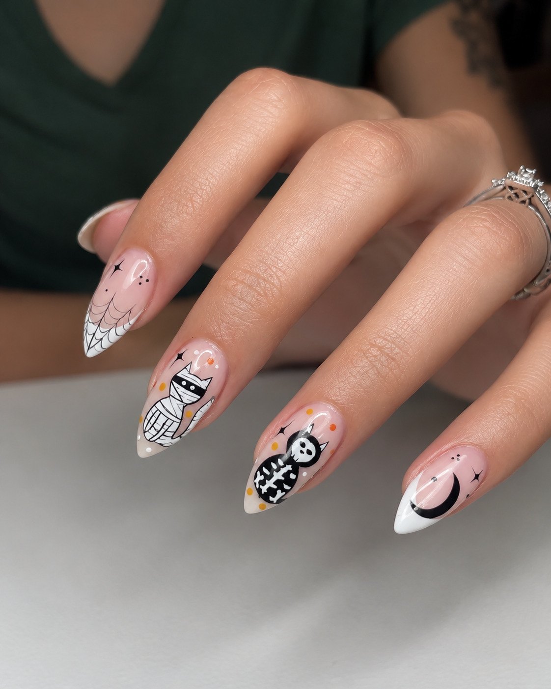 Almond Halloween nails with a mummy cat, a skeleton cat, a spiderweb tip and a crescent moon