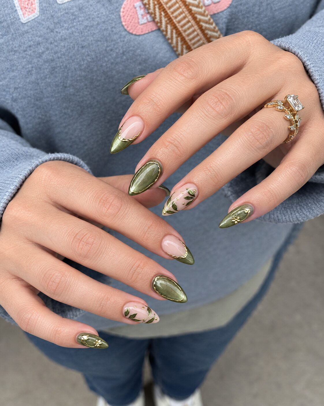Olive cat-eye almond nails framed in gold with painted olive leaves on nude accents