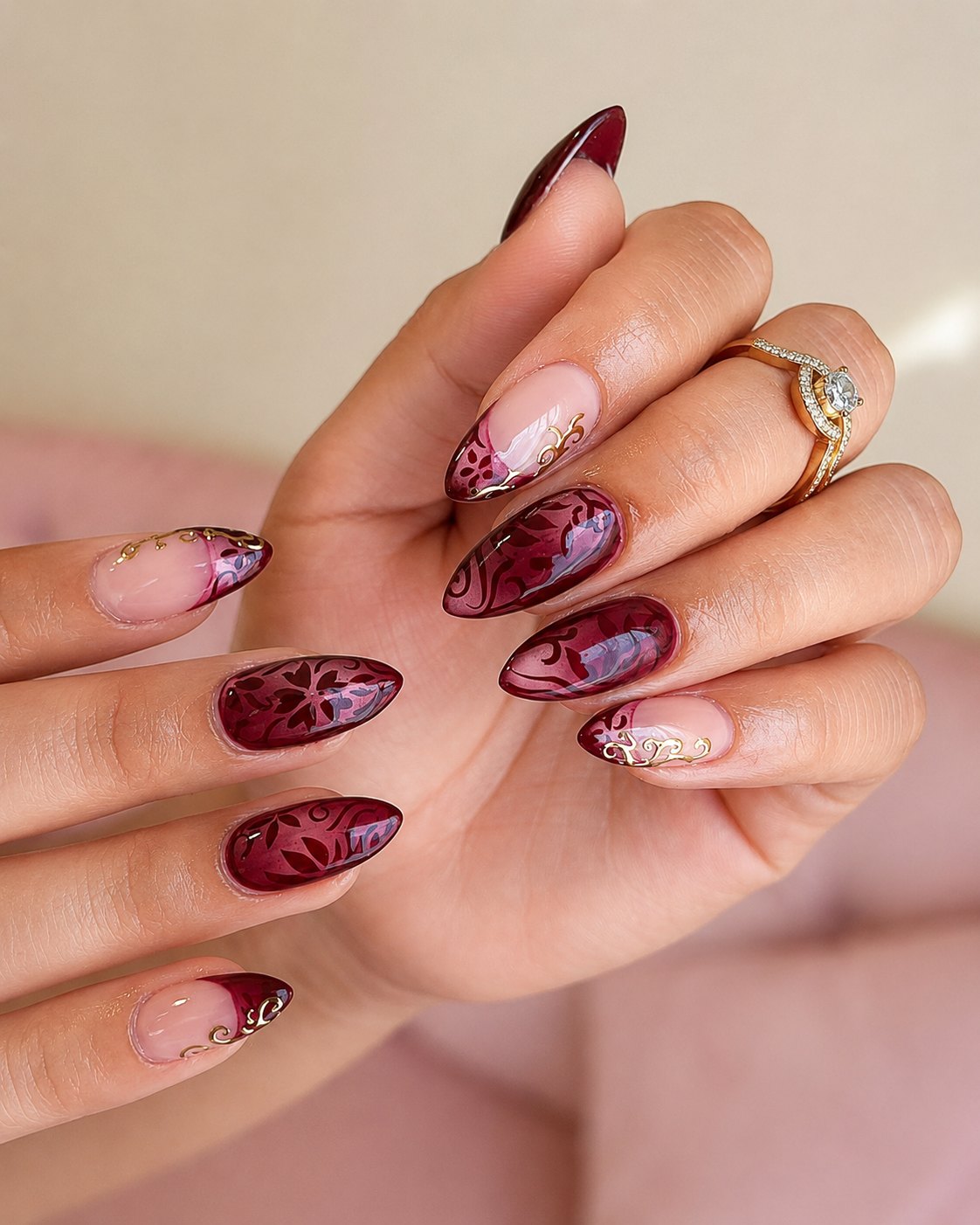 Deep burgundy cat-eye nails with baroque scrollwork and gold filigree tips