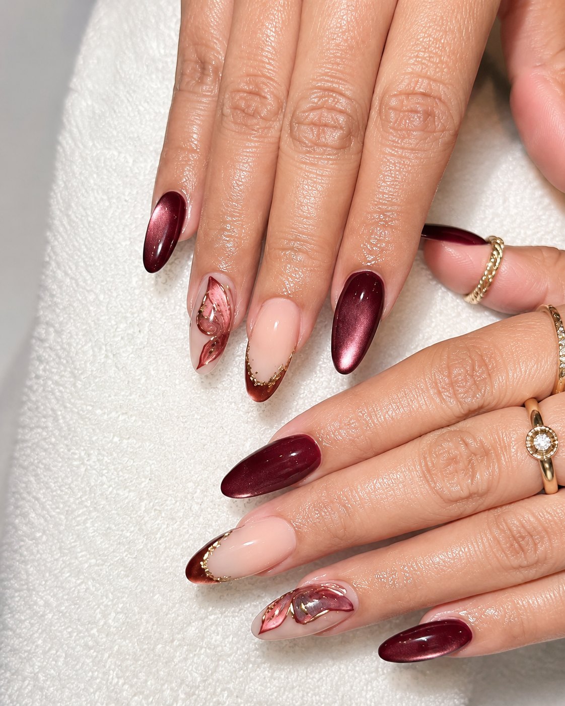 Merlot cat-eye nails mixed with sheer nude nails and rose petal art