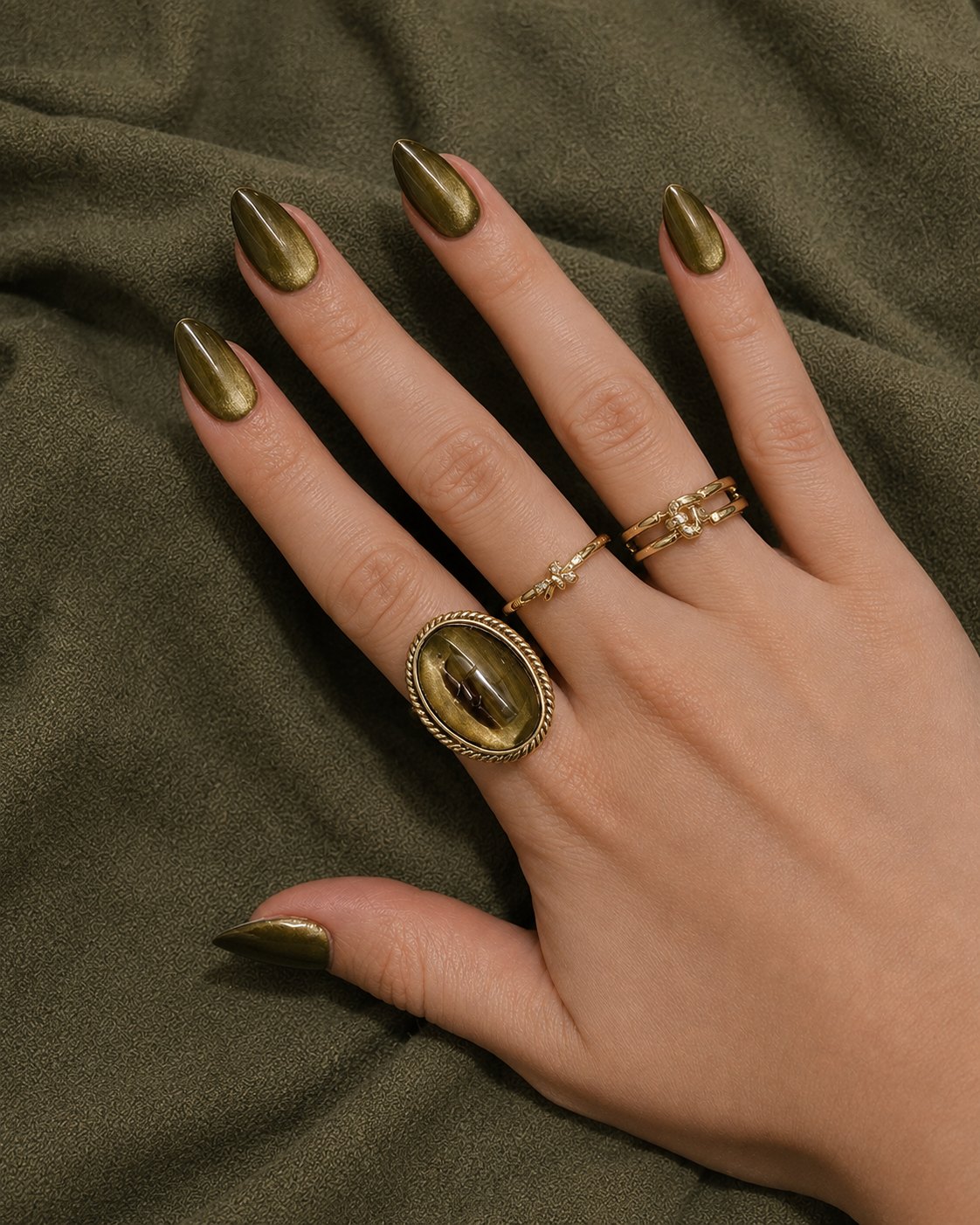 Moss green velvet cat-eye nails on almond shape against olive velvet