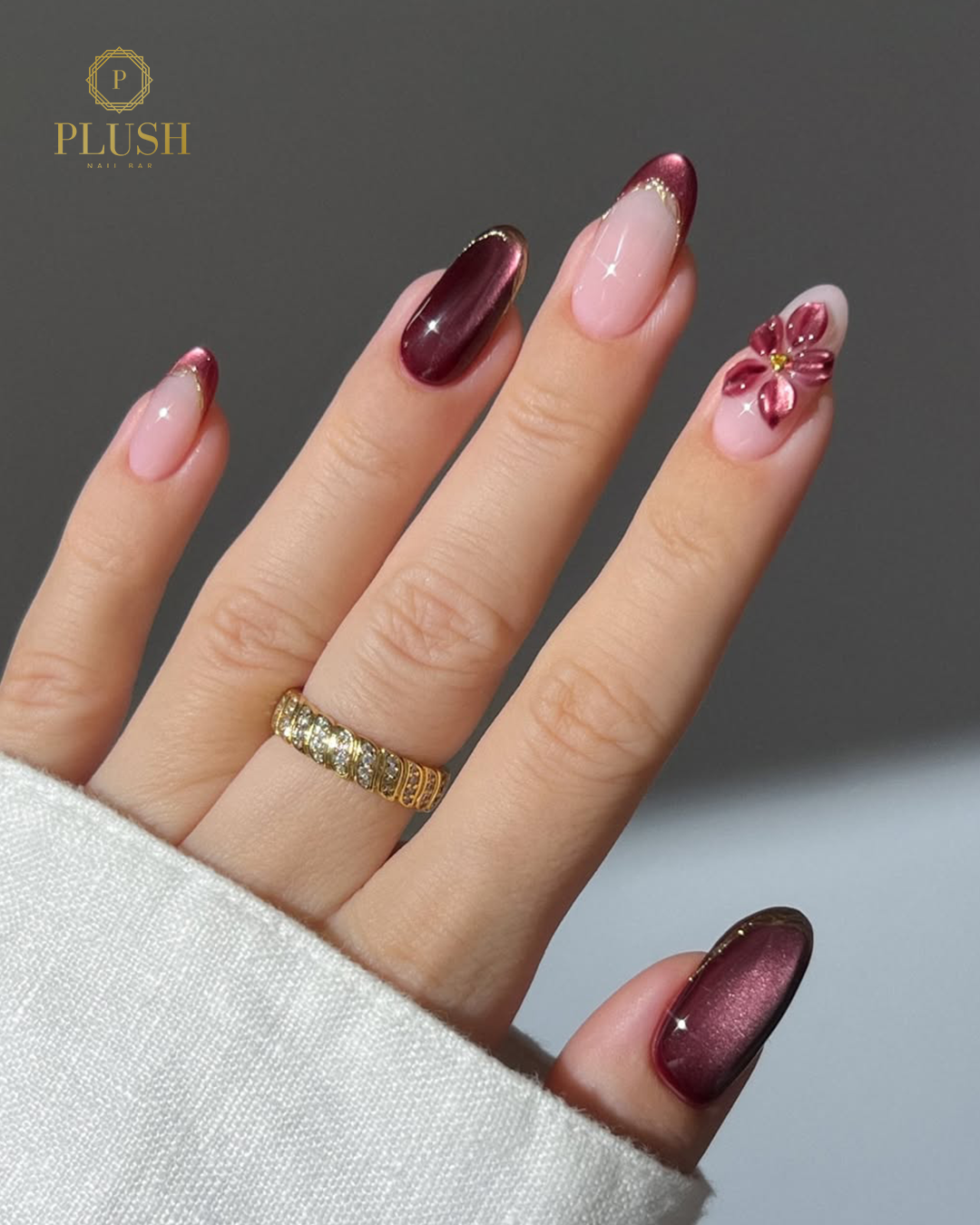 Luxury burgundy and gold valentine nails with floral accent at Plush Nail Bar